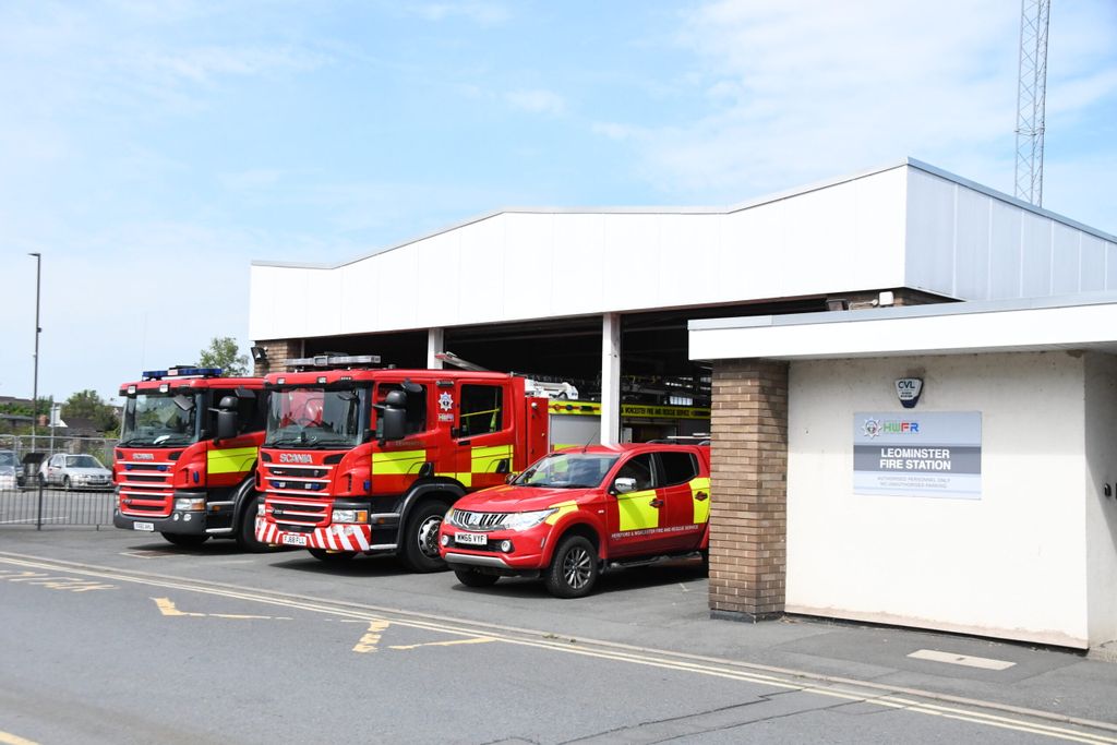 Three fire vehicles in front of fire station bays