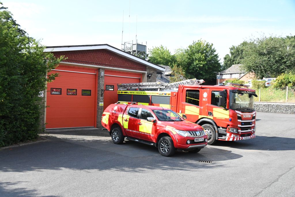 Fire vehicles in front of fire station bays with crew carrier in foreground