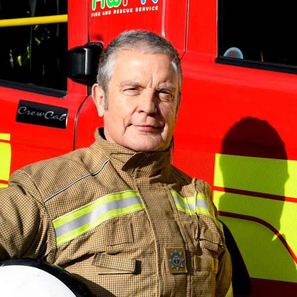 Firefighter smiling in front of red fire engine