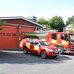 Fire vehicles in front of fire station bays with crew carrier in foreground