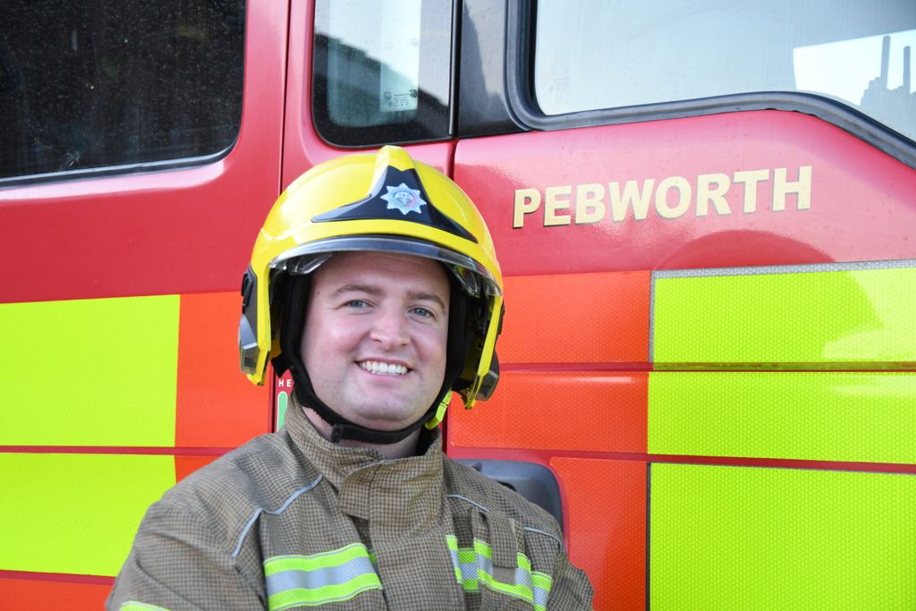 Firefighter in yellow helmet standing in front of fire engine