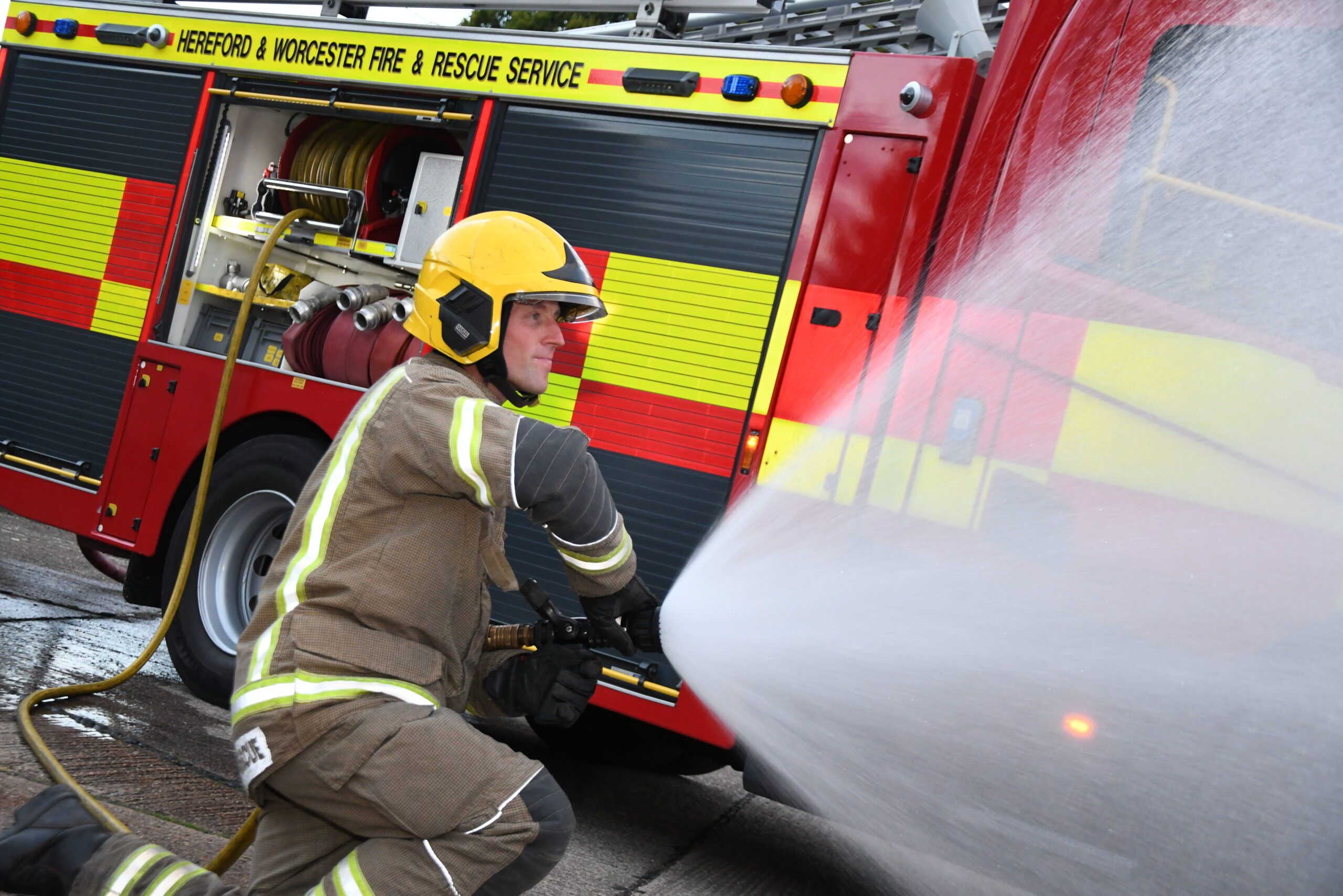 Firefighter in front of fire engine with water hose