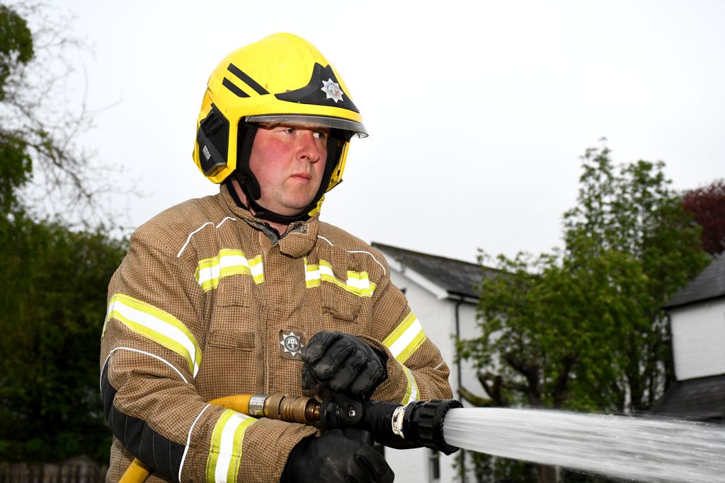 on-call firefighter with water hose