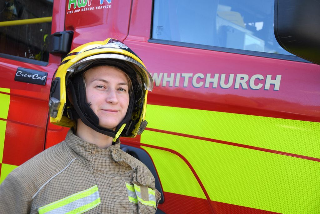 firefighter in helmet standing in front of fire engine